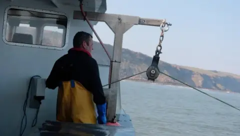 A fisherman on his boat out at sea