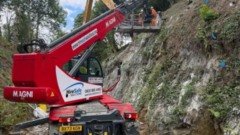 Machinery at works on the the C13 at Dinah’s Hollow - a road with steep tree-lined slopes.