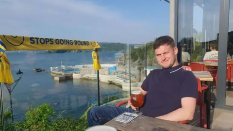 Leeds United fan Ed O'Brien sat down holding a glass.