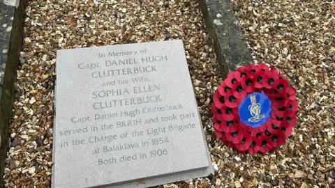 A grave with gravel and a clean, new stone plaque explaining that Captain Clutterbuck was in the Charge of the Light Brigade