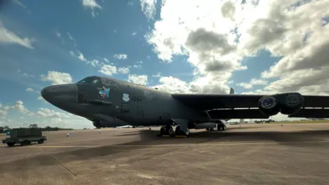 A grey plane on the ground with sunny skies above