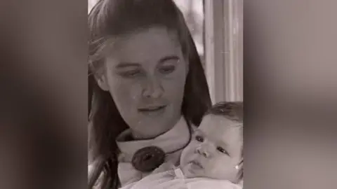 Helen Elkes A black and white photograph of Helen and her young baby Becky in 1970.