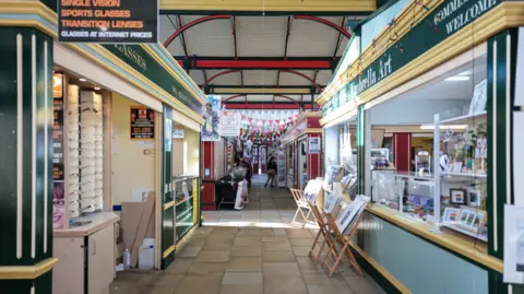 Kenny Brown The inside of the market with work displayed outside the art shop inside the covered market