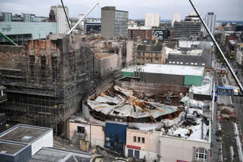 Getty Images A view of Glasgow from the rooftops. Two fire damaged buildings in the foreground - the circular ABC with its roof caved in and the blackened school of art. 