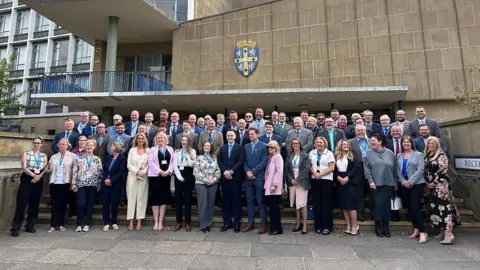 A large group of male and female councillors outside Durham County Council's county hall
