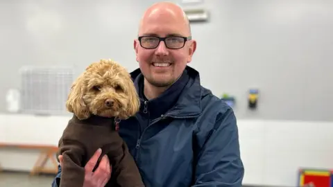 A man holds a dog