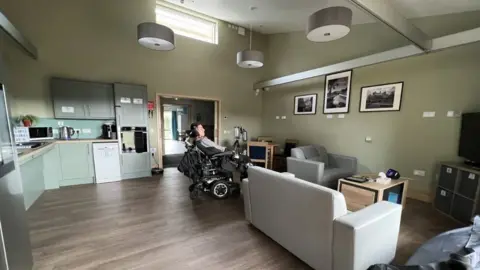 A picture of Jasper's room at college. There are smart devices and enough room for his wheelchair to move around the room.