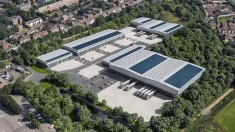 WMCA/Local Democracy Reporting Service An aerial image with four buildings with grey and blue roofs prominent in the centre of the photo. There are many trees around the area of the buildings and houses in the background.