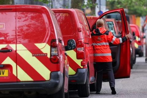 A postwoman enters a vehicle outside a Royal Mail collection office in London