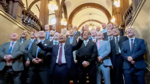 BBC Nigel Farage pictured on a staricase celebrating with team of councillors posing to have their picture taken.