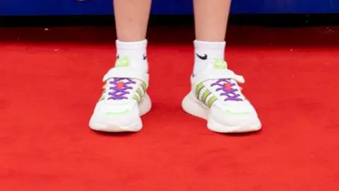 Disney A pair of white trainers on a dazzling red carpet