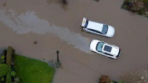 Reuters A drone shot of two cars left abandoned in brown flood waters 