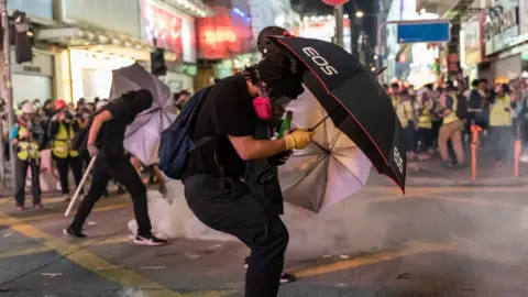 Getty Images Pro-democracy protesters react as police fire tear gas during a demonstration on October 20, 2019 in Hong Kong, China