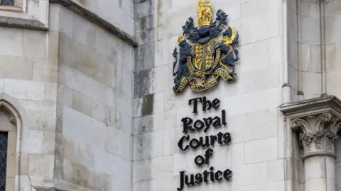 Getty Images A coat of arms on a grey brick wall, with lettering underneath that reads The Royal Courts of Justice