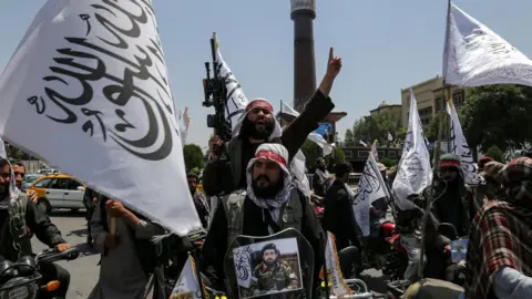 Supporters of the Taliban, some carrying guns and the white flag, celebrate the third anniversary of the group's takeover of Afghanistan.