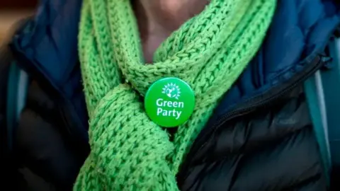 Unkown woman wearing a Green Party badge on a green scarf