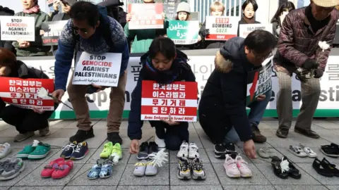 Activists place floral tributes on pairs of shoes symbolising Palestinian victims during a rally in South Korea