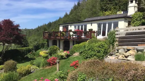 Aled Evans Daniel Andreas San Diego's home in Wales. A one story white bungalow with wooden balcony overlooking a rocky well tended garden. The house was bought from a local farmer for around £400,000.