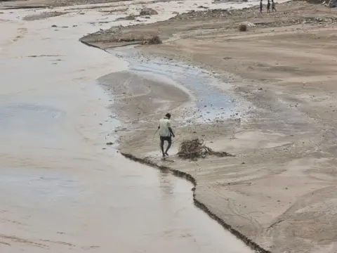     Reuters Een man loopt in de buurt van overstromingen na zware regenval in de provincie Hajjah in Jemen. 