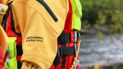 A close up of a firefighter wearing specialist waterproof equipment used to rescue people from the water.