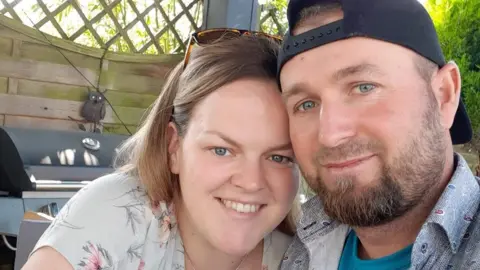 Erin and Visku Zdrava pose for a photograph together, both smiling into the camera.