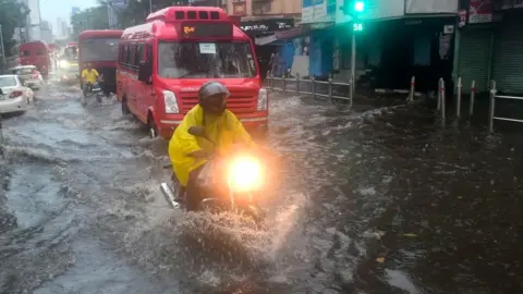 Getty Images People deal with the water clogging in the wake of Cyclone Tauktae at Dadar TT circle on May 17, 2021 in Mumbai, India.