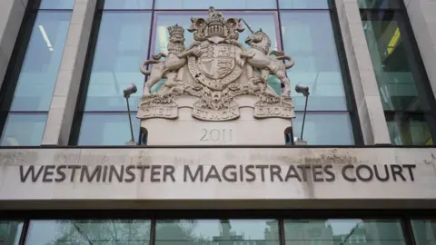 The exterior of Westminster Magistrates’ Court shows the building’s name in large letters beneath a stone coat of arms.
