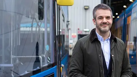 South Yorkshire Mayor Oliver Coppard, stood next to a blue bus.