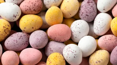 Easter mini eggs, chocolate in wooden bowl.