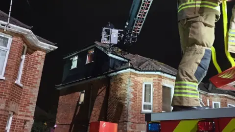 Dorset Police Firefighter operating turntable ladder to reach robbery suspect on roof