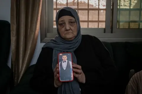 Rami's mother Rawia holds a photo of her son. "The bullet was in his heart," she said.