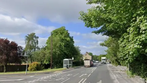 Streetview image of Manchester Road Tintwistle, a semi rural road with several cars going past a small group of houses
