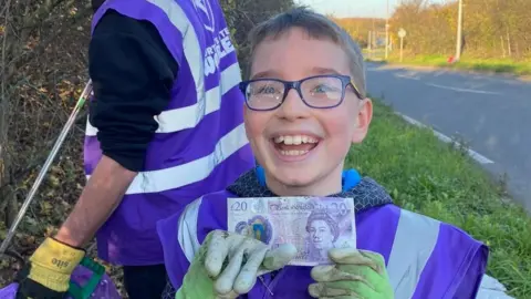 Northants Litter Wombles Evan holding a £20 note during a litter pick