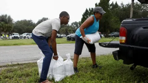 Reuters Shon Rodriguez and his parent  Millie load   the car   with sandbags, arsenic  they are distributed to Pinellas County residents earlier  the expected accomplishment  of Tropical Storm Milton, successful  Seminole, Florida, U.S. October 6, 2024