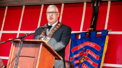 Royal Black Institution Sovereign Grand Master Rev William Anderson standing behind a podium on a stage.