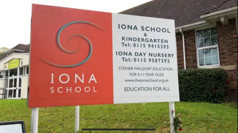 School sign outside a building giving contact details for the Iona School