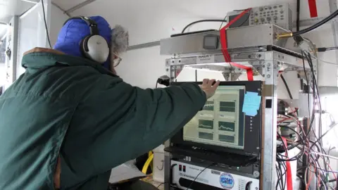 Anja Rutishauser A scientist with their back turned, operating radar equipment aboard an aircraft