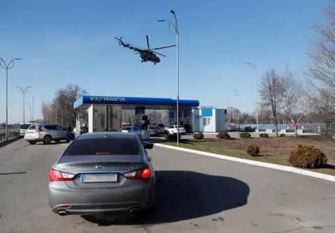 Reuters Ukrainian military helicopter flies over a gas station, after Russian President Vladimir Putin authorized a military operation in eastern Ukraine, outside the city of Dnipro, Ukraine 24 February 2022