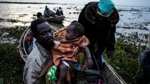 AFP Internally displaced Congolese return to the shore line of lake Albert after spending the night out in the lake for safety on March 05, 2018 in Tchomia.