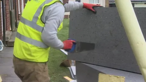 Workman cutting insulation with a saw