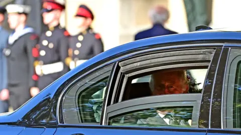 Pacemaker King Charles smiles and looks out through a window of the car taking him to St Anne's Cathedral in Belfast