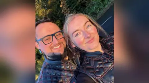 Ryan Crawford and Laura Burrows together posing for a selfie and wearing their bike leathers. 