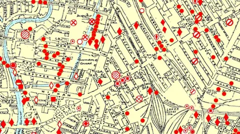 Rob Haywood An overhead view of a yellow map of a city with named streets drawn in black and waterways marked in blue. Red circles and diamonds denote where bombs fell.