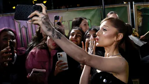 Getty Images Ariana Grande takes a selfie with fans at the 