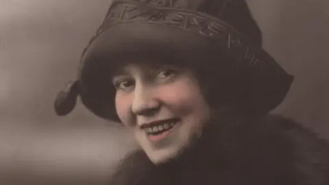 An Iodhlann An archive photograph of a woman wearing a hat and scarf 