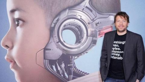 Gareth Edwards in front of a picture of a child cyborg