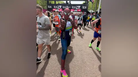 Daniel Rusby A man in a Spider-Man costume poses by the finish line of the London Marathon.