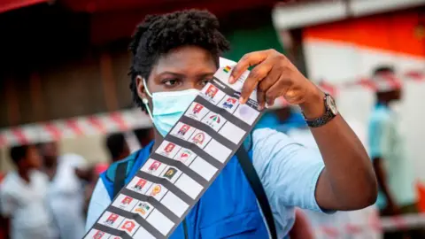 AFP An archive shot from 2020 showing an electoral official wearing a face mask inspecting a ballot paper.