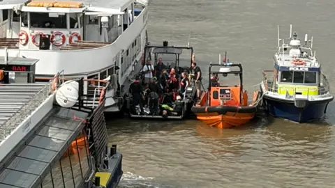 Rescue boats and a Met Police boat next to each other in the Thames. 