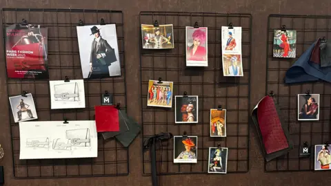 Three separate wire racks, each of them has photos and sketches from Gáinne Maher's collections pinned onto the wires. They are attached to a brown wall in the back. 